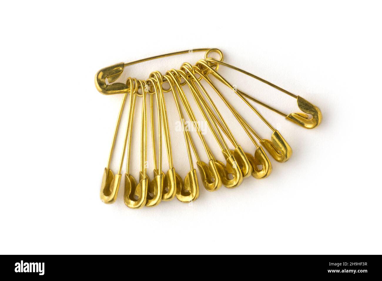 gold color safety pins, commonly used to fasten clothing, isolated on white background Stock Photo