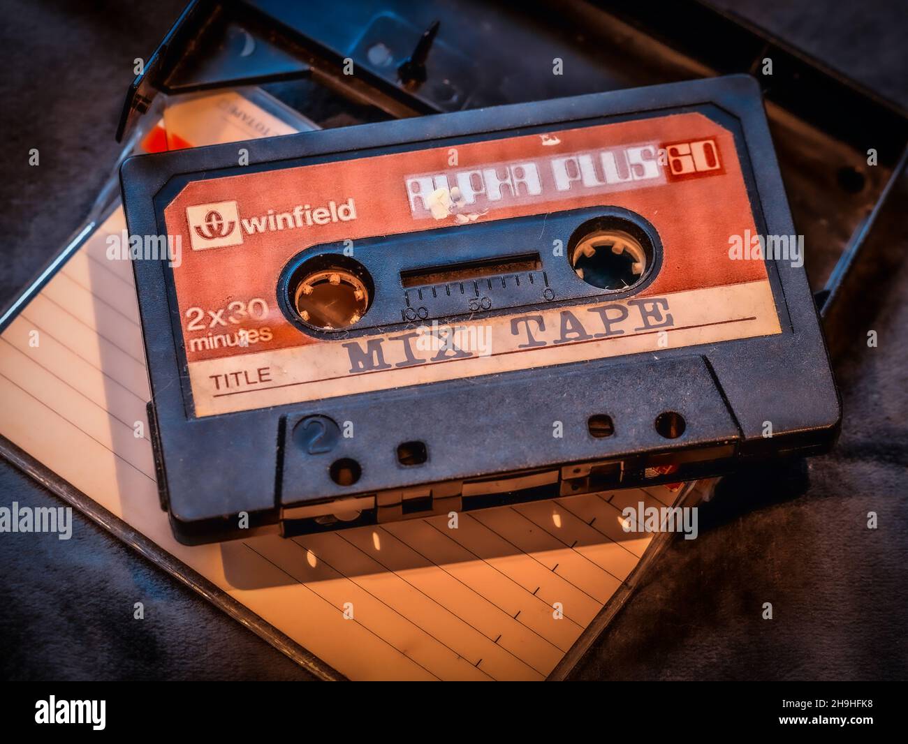 Retro Alpha plus 60 Winfield dogeared vintage cassette with Mix Tape written across the title area on a empty cassette case holder in the background Stock Photo