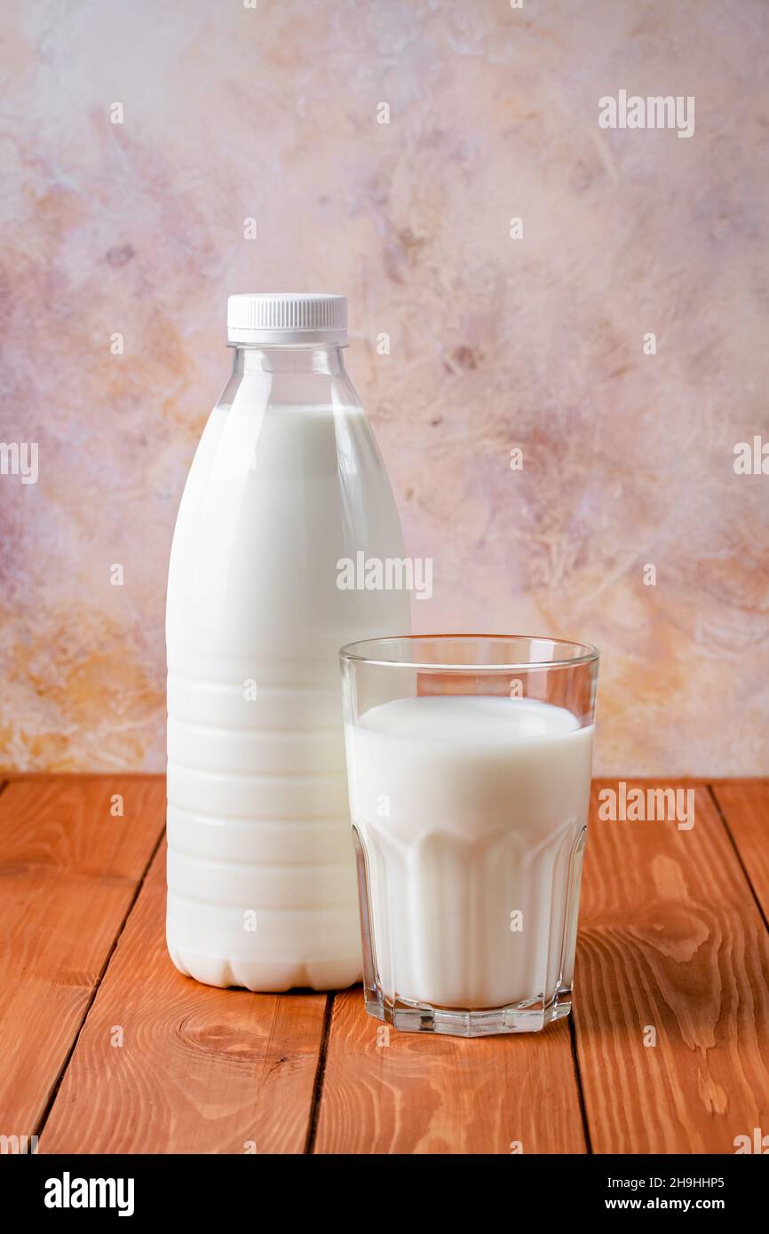 Bottle and glass of milk on a brown wooden table. Food background, cooking ingredient, drink. Healthy food, a source of calcium Stock Photo