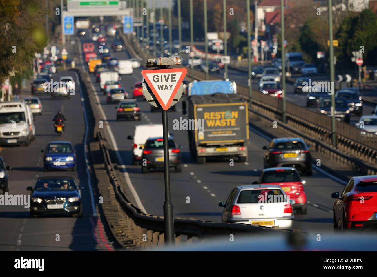 Traffic on the A3 Bypass driving past a Give Way sign heading towards New Malden and Tolworth on a bright and dry late winters afternoon. Stock Photo