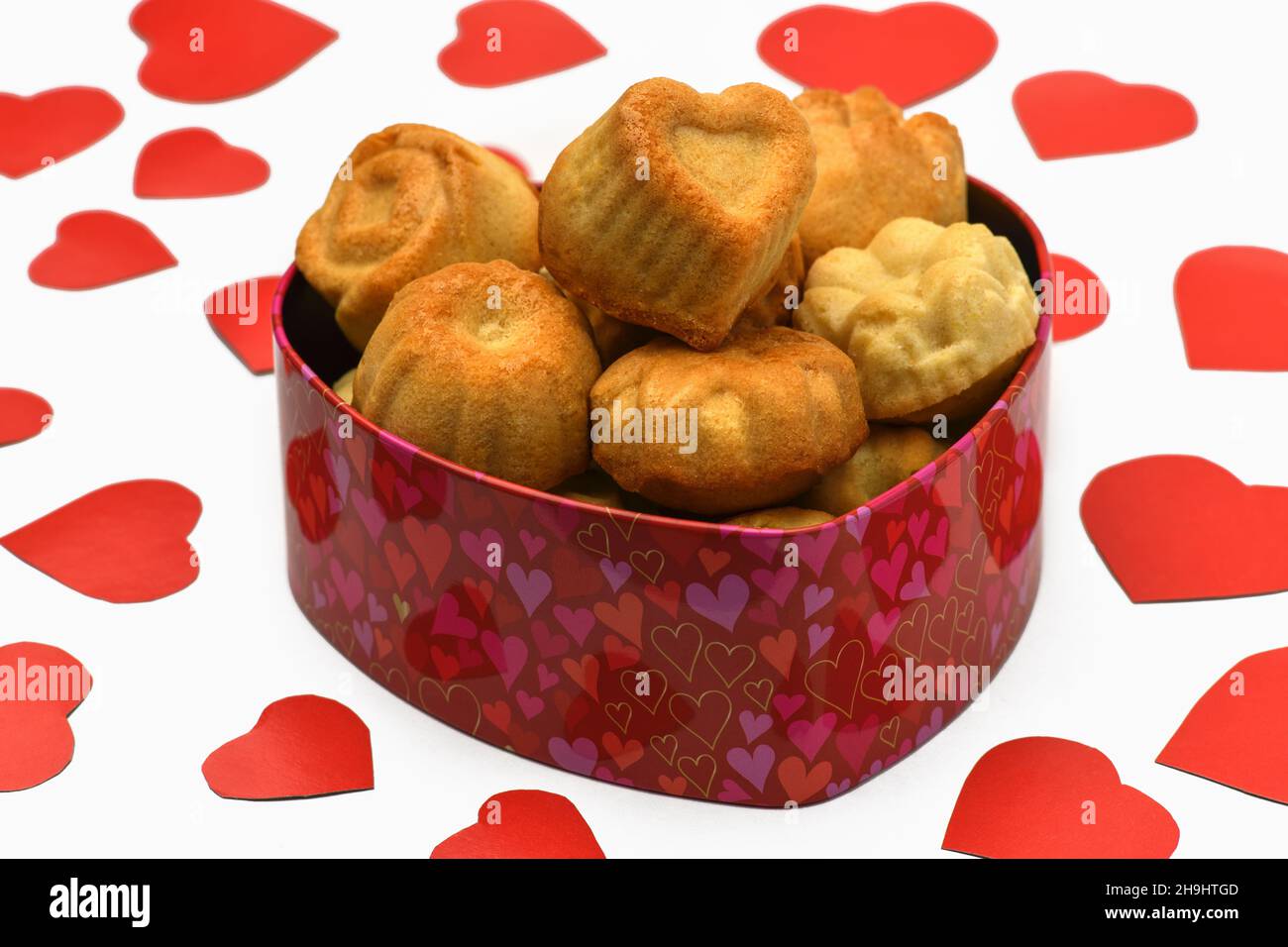 Isolate. Valentine's day. Box in the shape of a heart in it a lot of cupcakes, cookies, lie next to a lot of red carved hearts. Horizontal photography Stock Photo