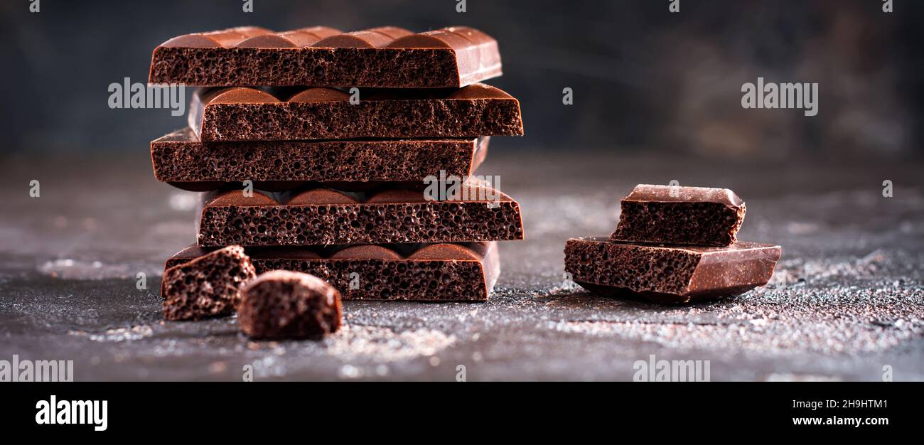 Stack of bitter porous airy chocolate on dark old background. Selective focus. Stock Photo