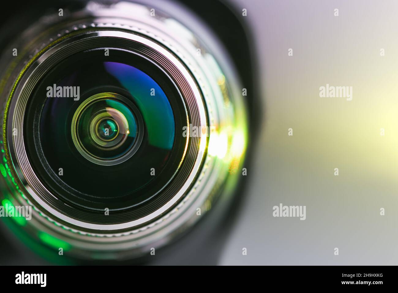 The camera lens and yellow backlighting. A beam of yellow on a grey background. Horizontal photo Stock Photo