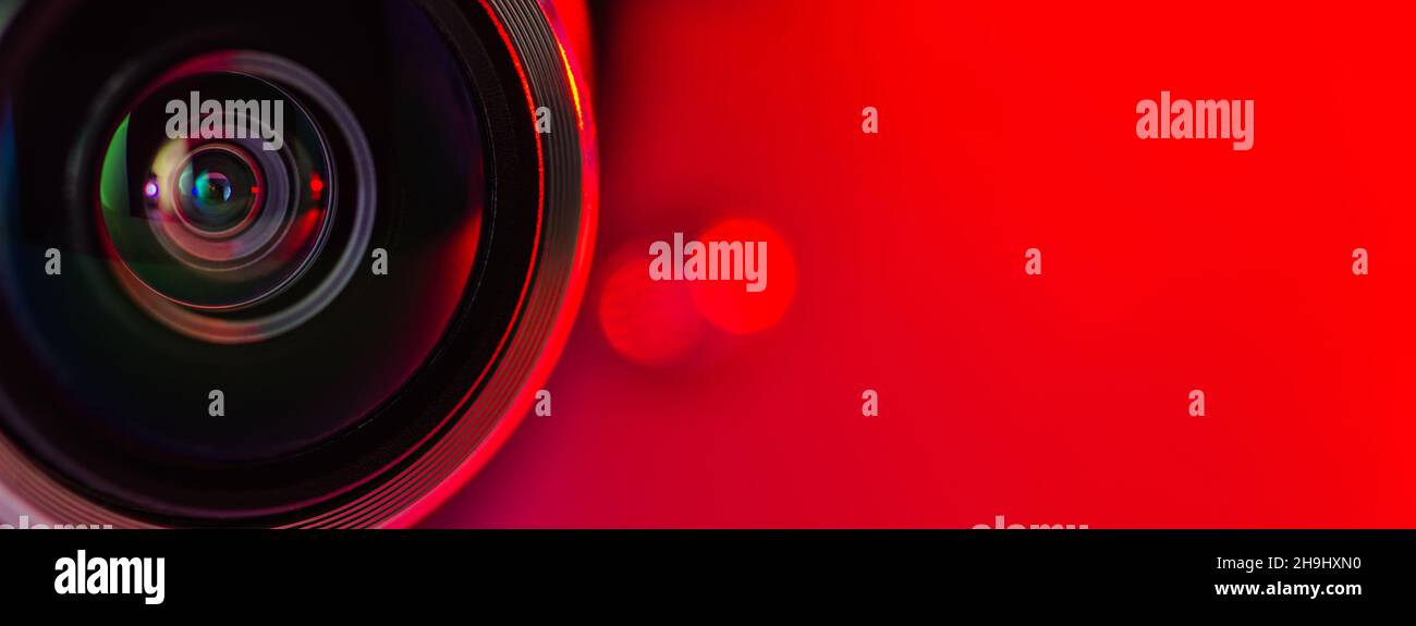 The camera lens and the red backlighting. Red  camera Lens close Up. Banner Stock Photo