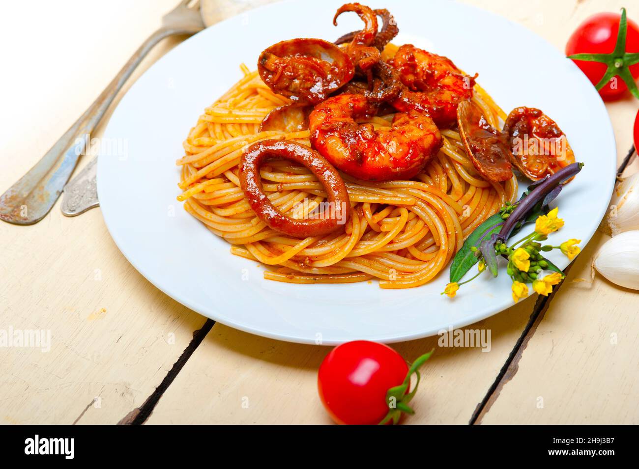 Italian seafood spaghetti pasta on red tomato sauce over white rustic