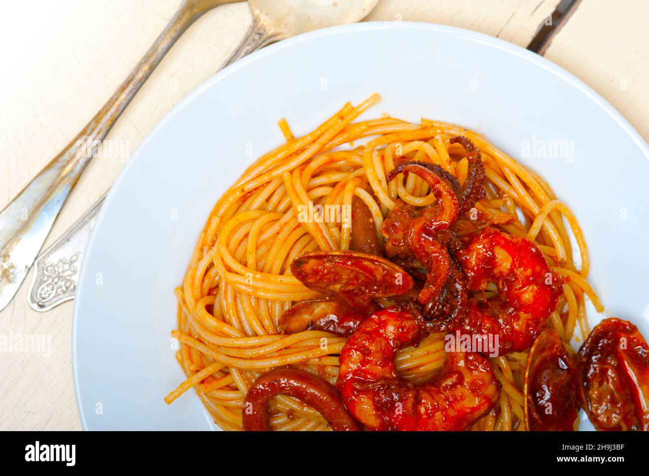 Italian seafood spaghetti pasta on red tomato sauce over white rustic
