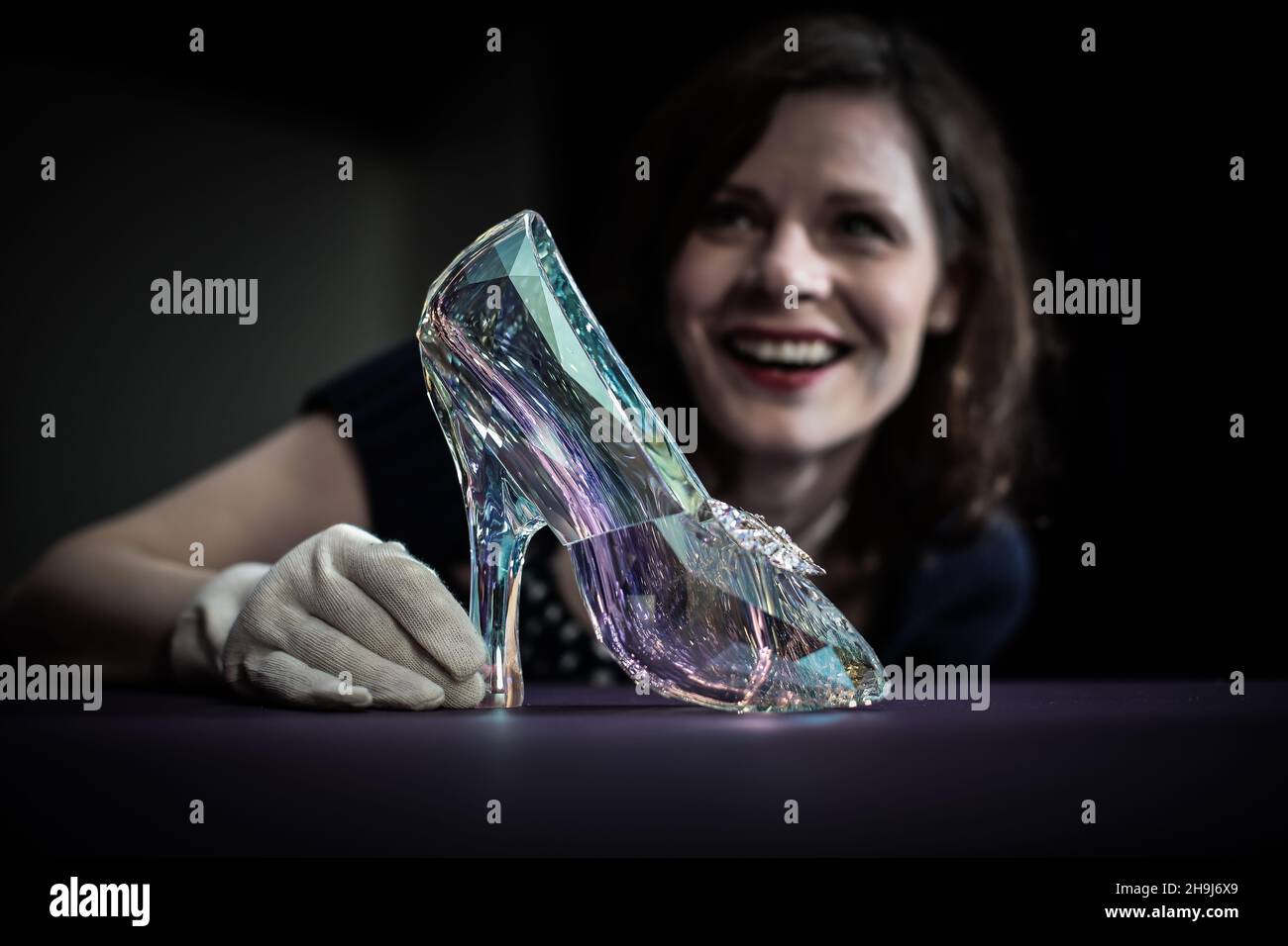helen persson curator of the shoes pleasure and pain exhibition at the victoria and albert museum in london poses with a crystal swarovski slipper made for disneys cinderella film designed under the direction of academy award winning costume designer sandy powell the slipper has 221 facets in a light reflecting crystal blue aurora borealis coating 2H9J6X9