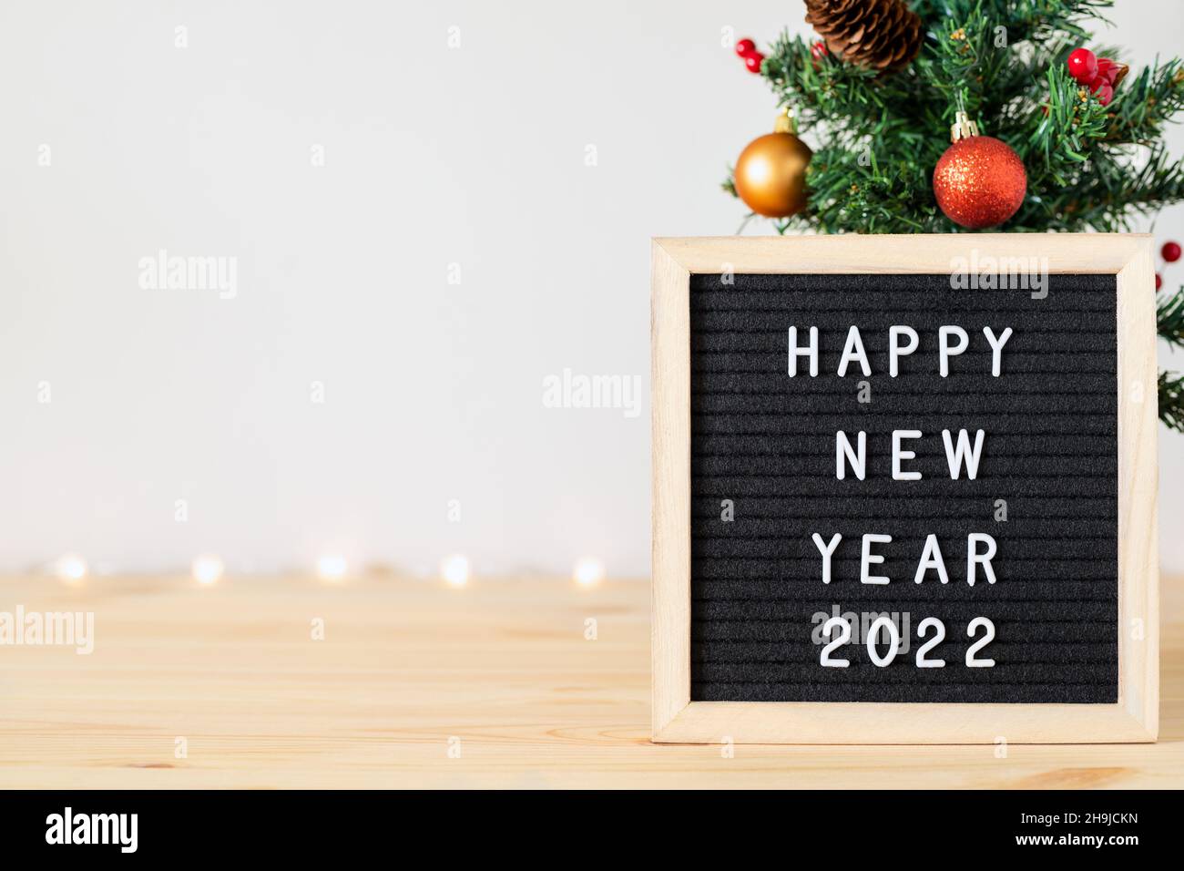 Happy new year 2022 text on felt letter board and Christmas tree with holiday decorations on table. Copy space on one side for text Stock Photo