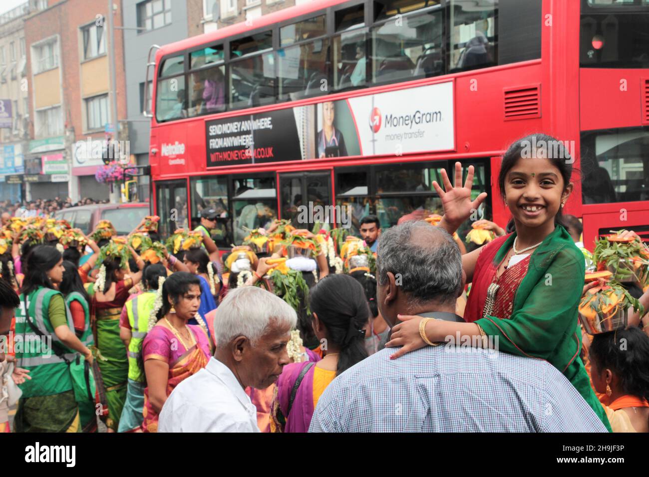 Women carrying pots of milk on their heads, known as paal kudam, during a chariot procession which is the culmination of the annual Shri Kanagathurkkai Amman Temple (SKAT) festival of Thaipusam in West Ealing. The festival attracts thousands of Hindu devotees to West Ealing from all over the world. Stock Photo