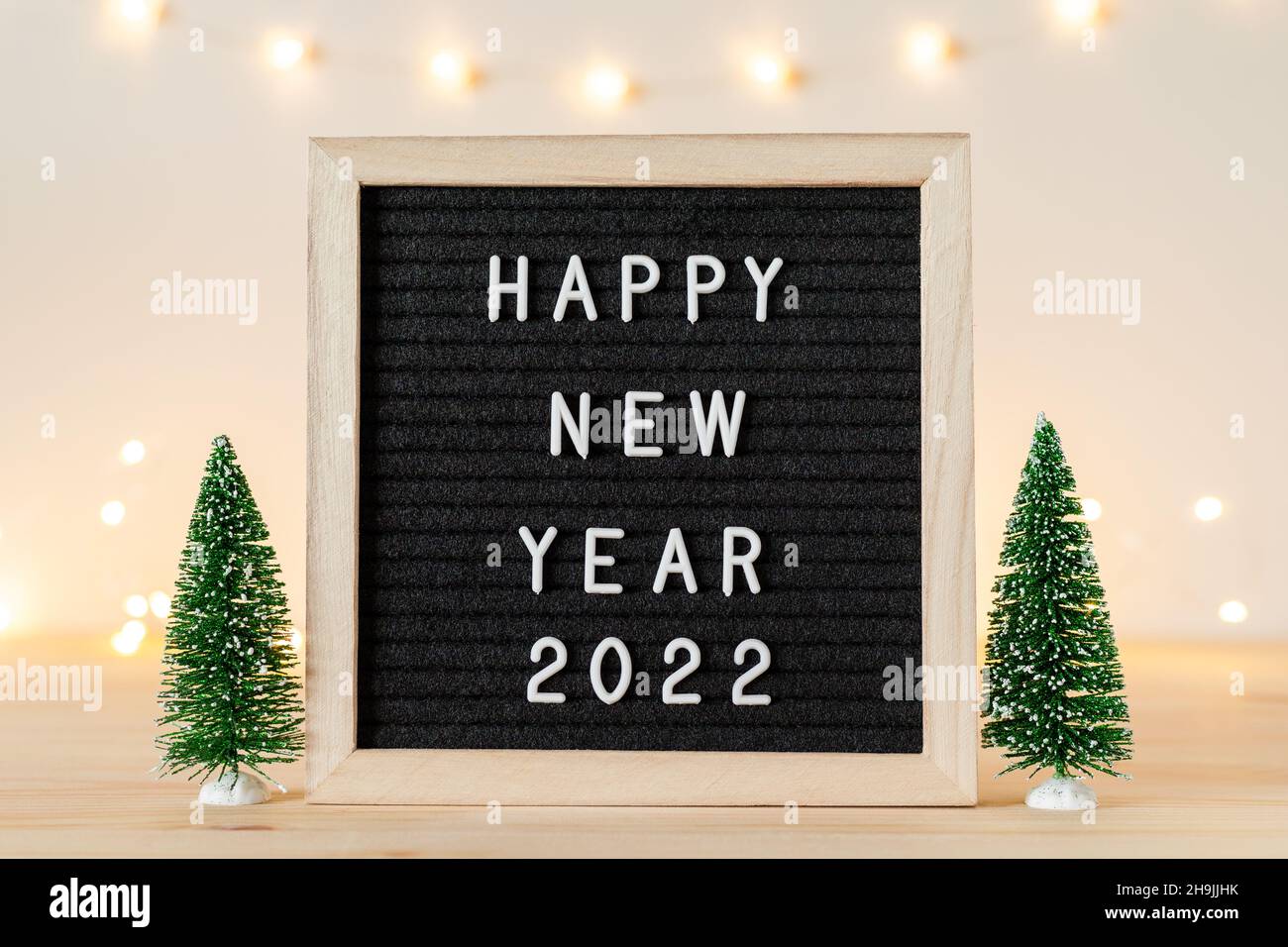 Happy New Year 2022 Greetings On Letter Board With Holiday Lights And Small Decorative Christmas Trees On Wooden Table. Copy Space For Text Stock Photo - Alamy