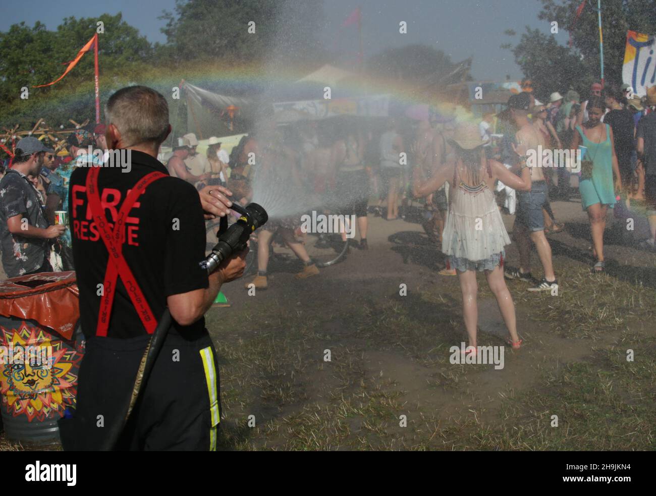 A woman is doused by Shepton Mallet firemen creating a rainbow effect on a very hot Day 1 (Wednesday) of the 2017 Glastonbury Festival at Worthy Farm in Somerset. Photo date: Wednesday, June 21, 2017. Photo credit should read: Richard Gray/EMPICS Entertainment Stock Photo