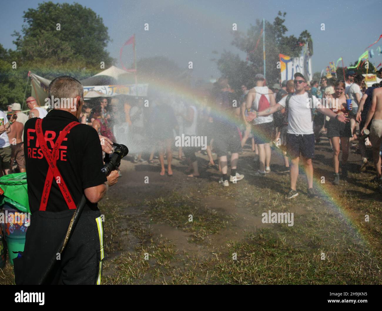 A man is doused by Shepton Mallet firemen creating a rainbow effect on a very hot Day 1 (Wednesday) of the 2017 Glastonbury Festival at Worthy Farm in Somerset. Photo date: Wednesday, June 21, 2017. Photo credit should read: Richard Gray/EMPICS Entertainment Stock Photo