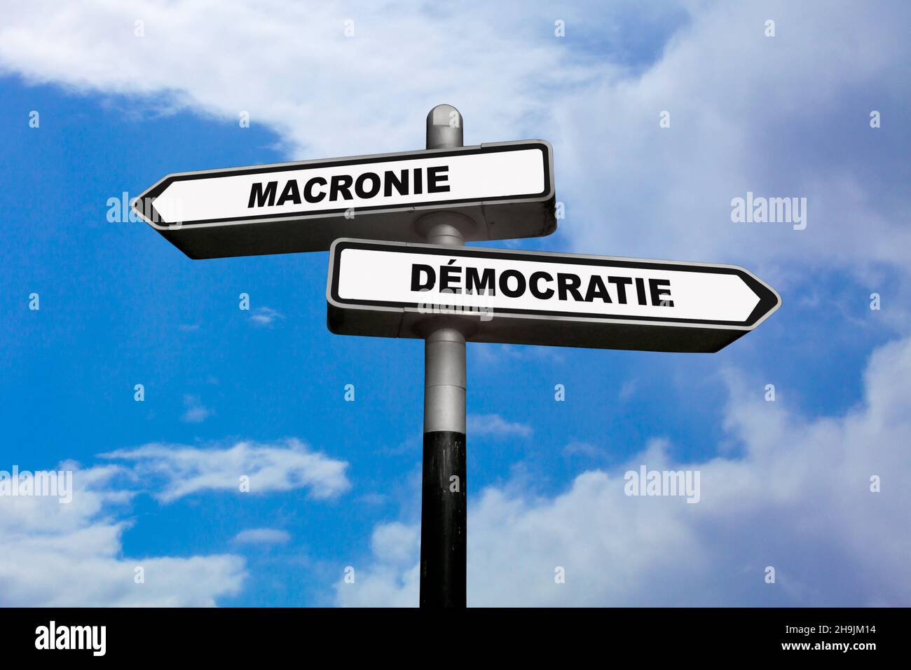 Two direction signs, one pointing left and the other one, pointing right, with written in them in French : Macronie / Démocratie Stock Photo