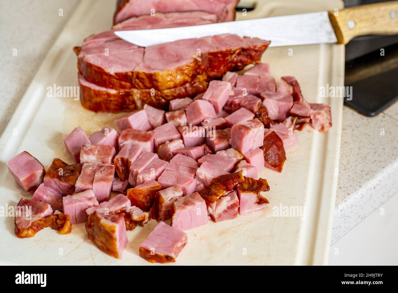 Smoked meat cut into cubes and sliced meat on white kitchen board with
