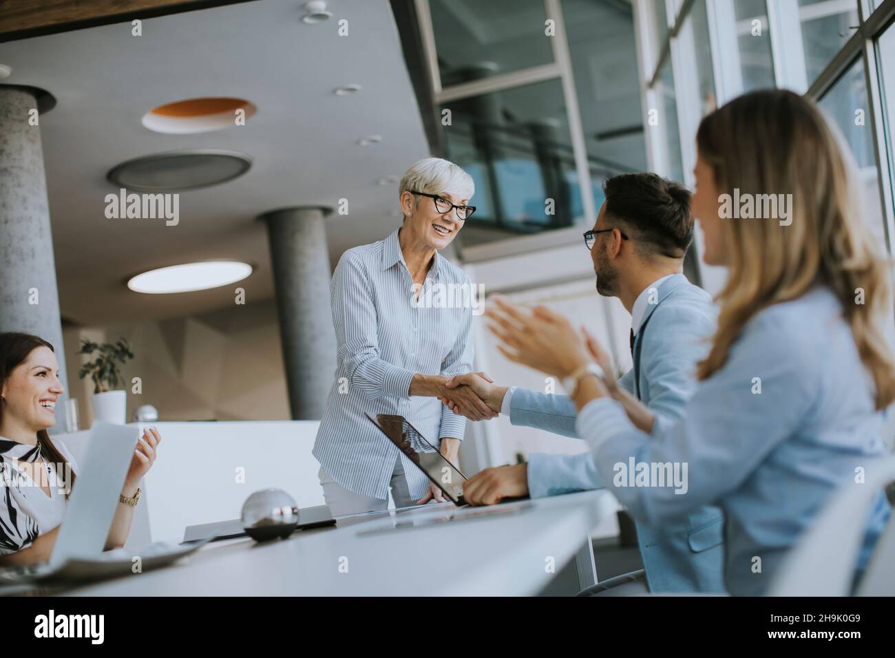 Mature business woman handshaking with young colleague on a meeting in the office Stock Photo