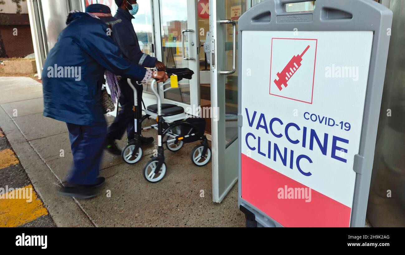 Sign of the Covid-19 Vaccine Clinic with the motion-blurred image of a senior adult pushing a walker. Stock Photo