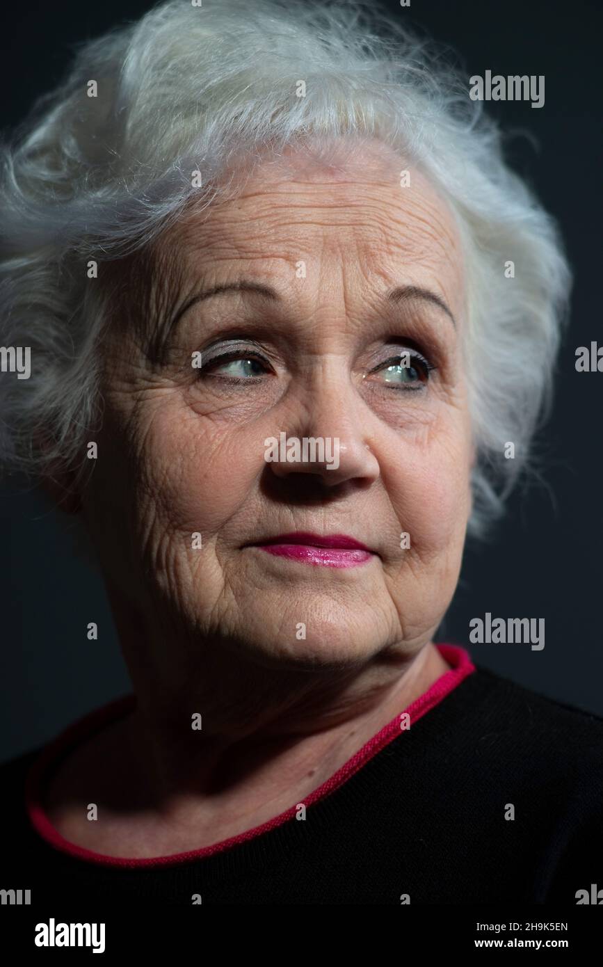 portrait of a blonde grandmother close-up on a dark background Stock Photo