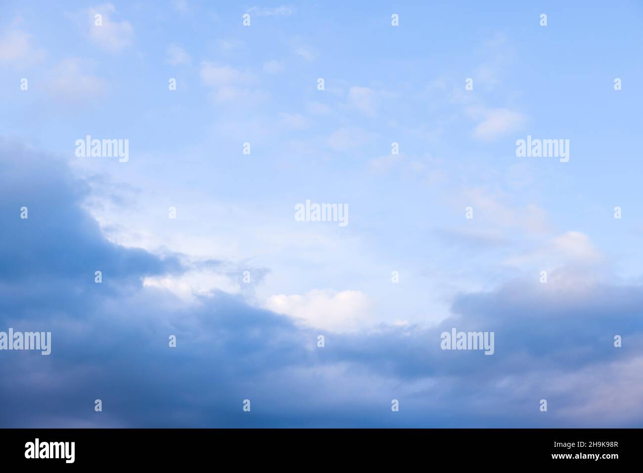 Dark rain clouds against a blue sky background, ideal for a moody sky background Stock Photo