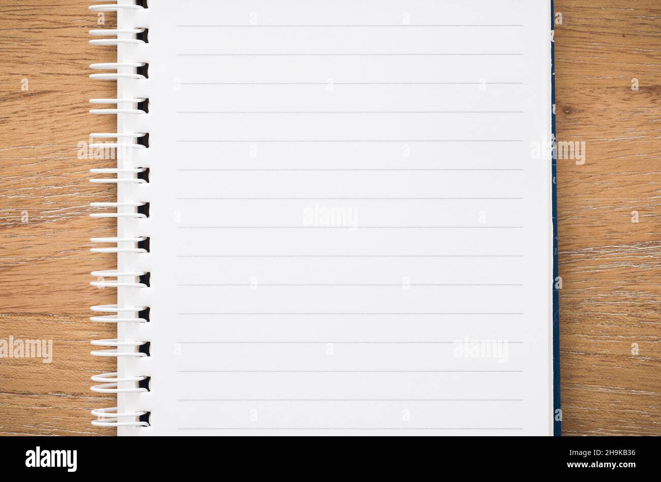 Closeup of empty lined notebook open on a wooden desk, from above. Flat lay template, border or background with copy space Stock Photo