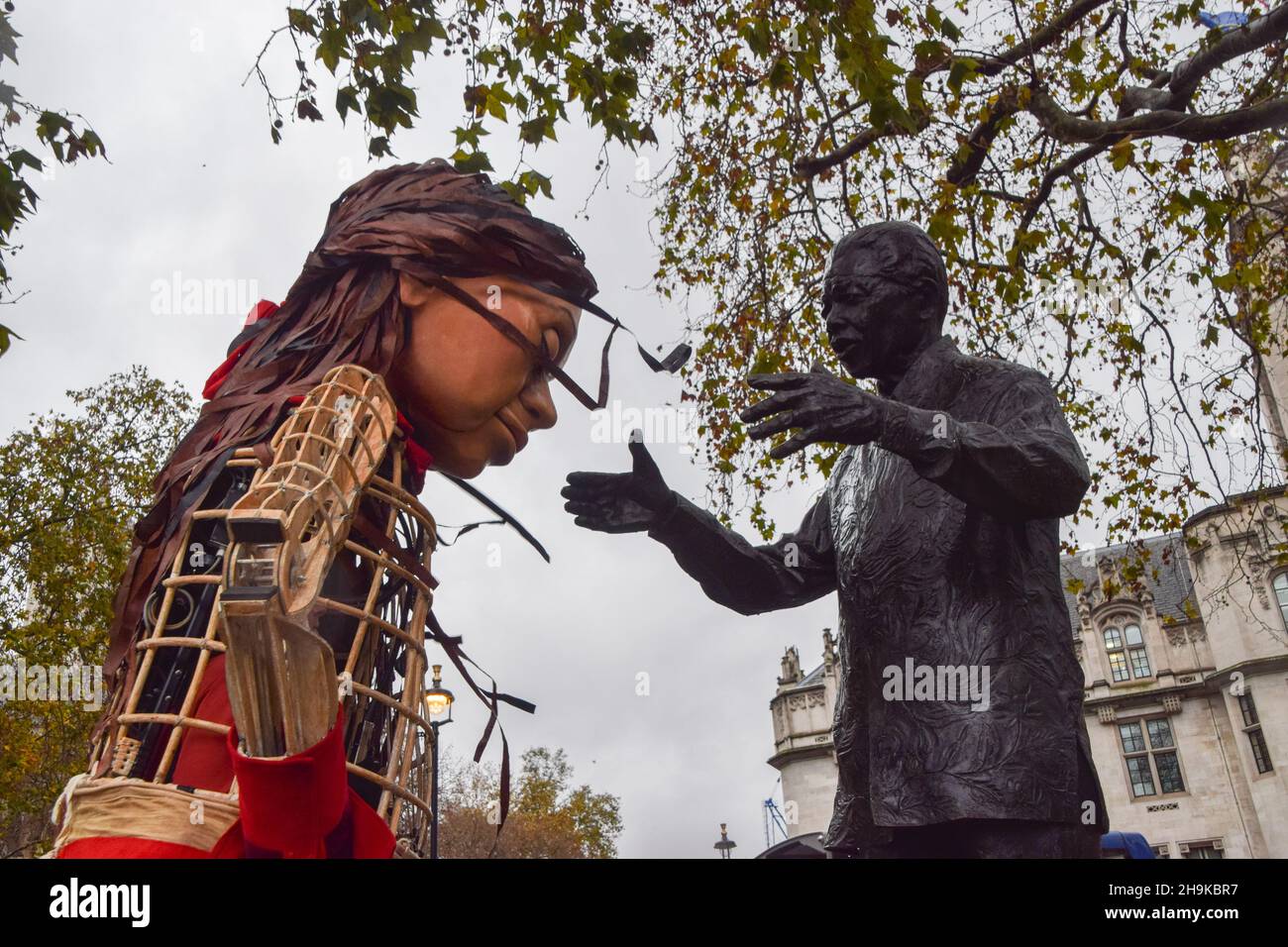 London, UK. 7th December 2021. Little Amal and the statue of Nelson Mandela. Demonstrators gathered at Parliament Square with the puppet Little Amal in support of refugees and in opposition to the Nationality and Borders Bill, which was debated by the government. Credit: Vuk Valcic / Alamy Live News Stock Photo