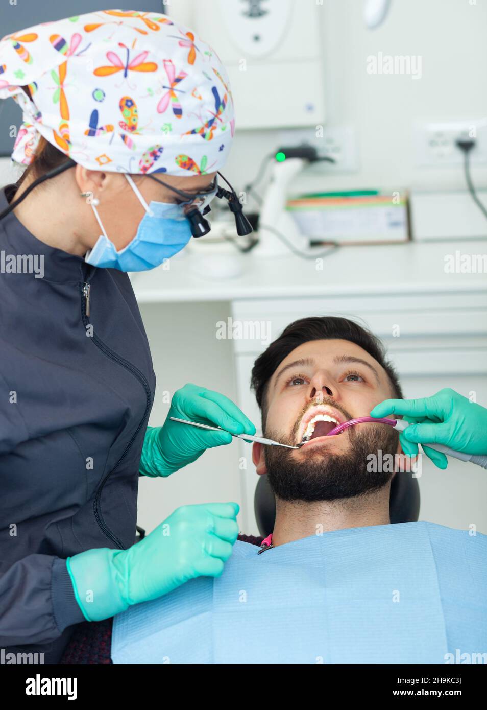 Female dentist examines a man patient in a dental office using professional tools and personal protective equipment. Stock Photo