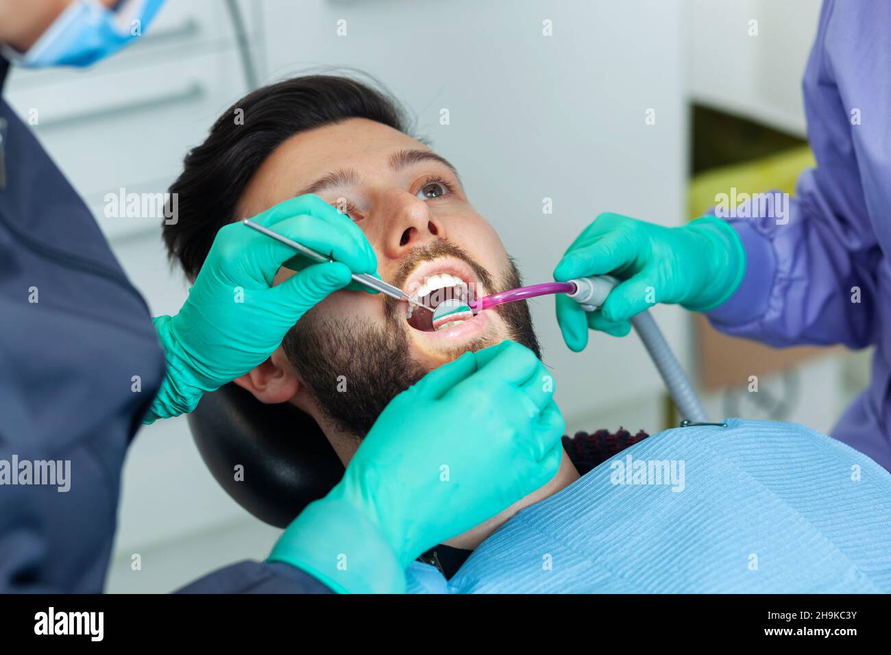 Female dentist examines a man patient in a dental office using