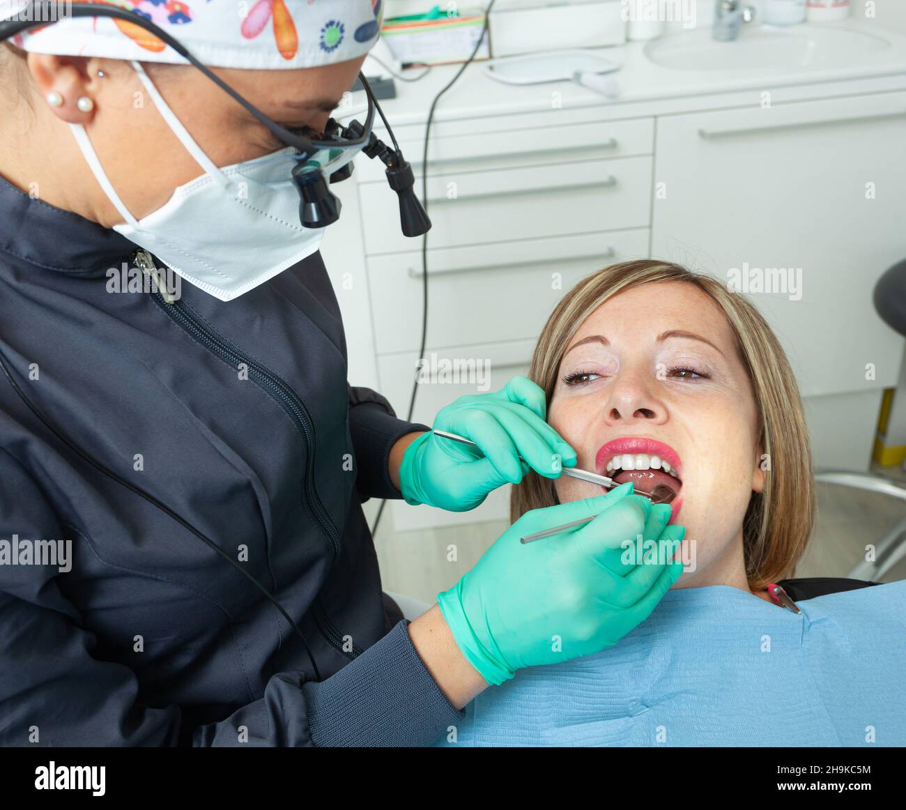 Young Blonde Female patient with open mouth examining dental inspection at dentist office. Stock Photo