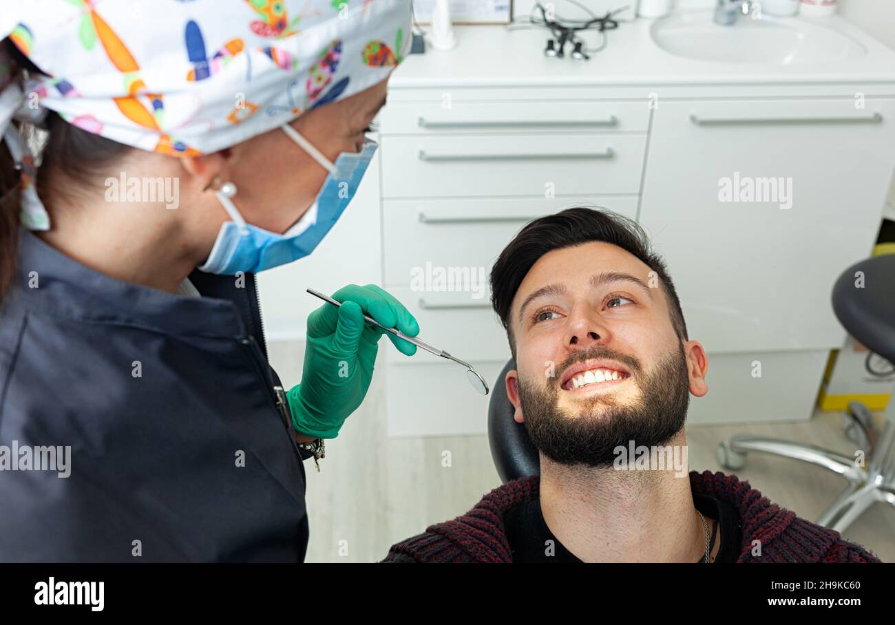 Female dentist examines a man patient in a dental office using
