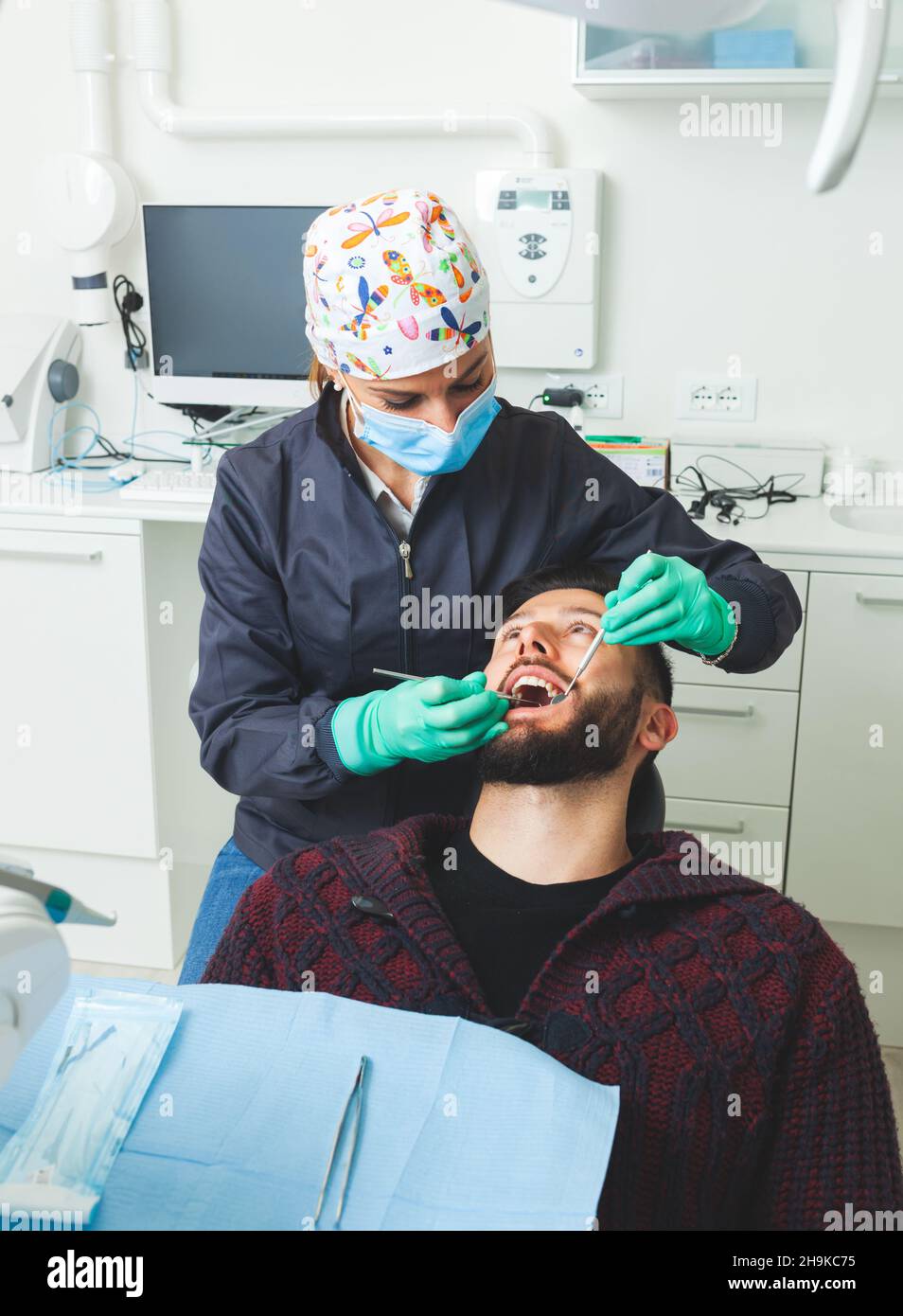 Female dentist examines a man patient in a dental office using
