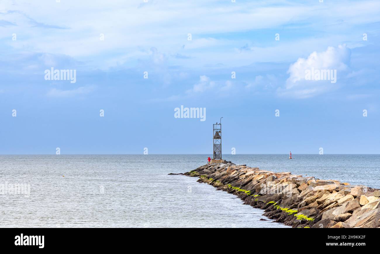 two men fishing at the end of a long breakwater in Montauk Stock Photo