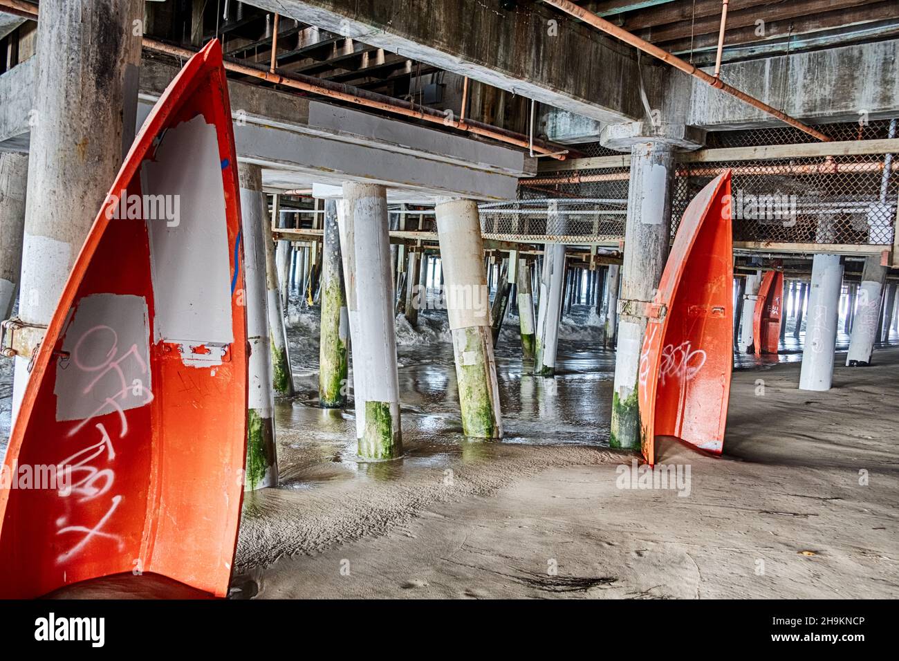 SANTA MONICA, CALIFORNIA - SEPTEMBER 29, 2019: A view of the pilings and old wood lifeguard rescue boats under the Santa Monica pier. Stock Photo
