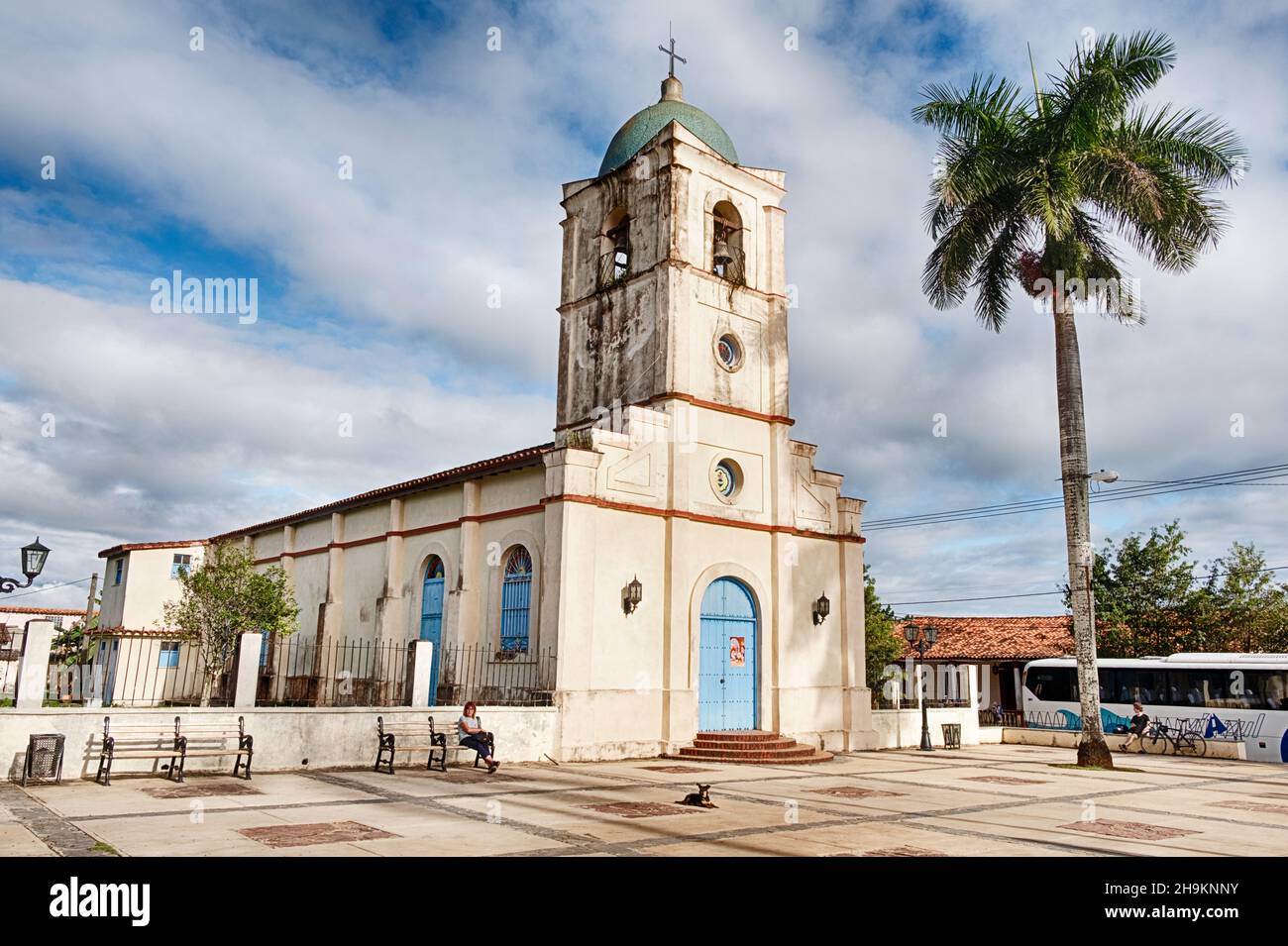 VINALES, CUBA - DECEMBER 25, 2019: On Christmas Day, one anonymous person sits on a bench on the plaza in front of the main church in Vinales, Cuba Stock Photo
