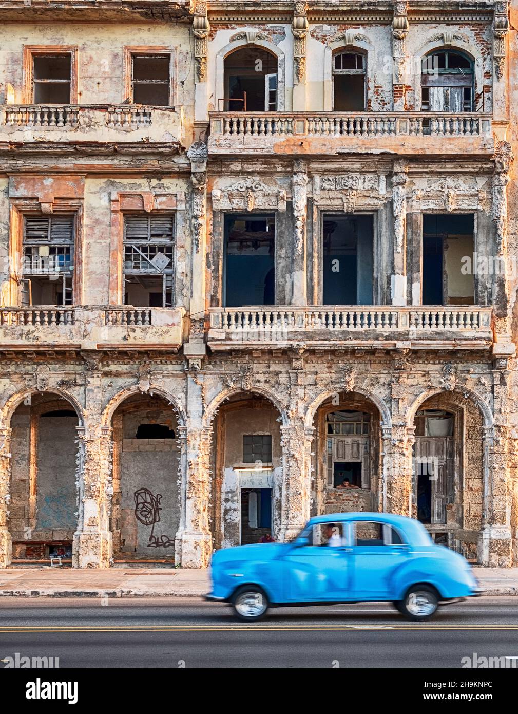 HAVANA, CUBA - DECEMBER 31, 2019: An anonymous man drives a vintage American car as a taxi on the Malecon waterfront road in front of an old building. Stock Photo