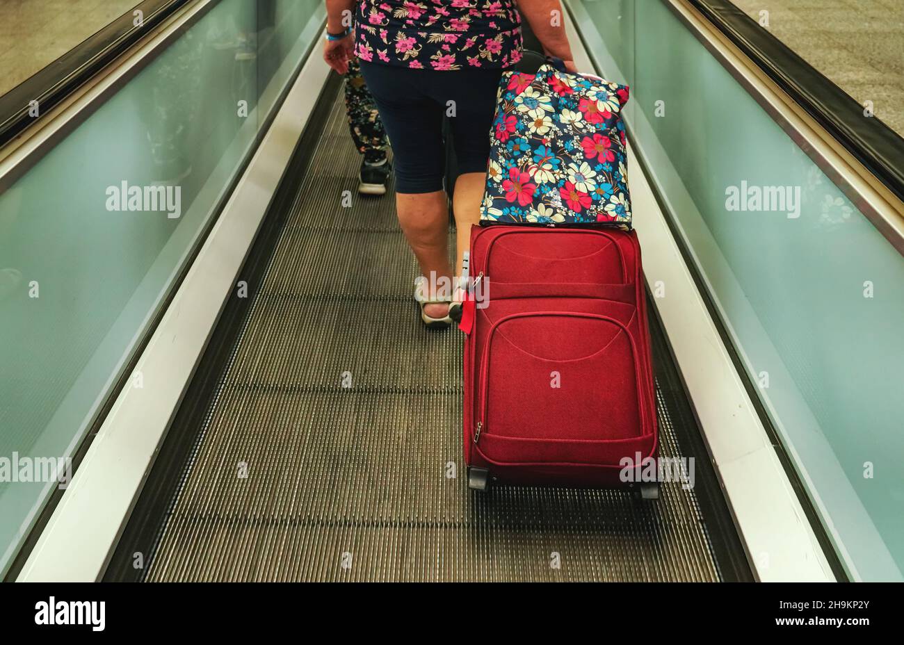 Senior woman standing at moving walkway (flat elevator) in airport