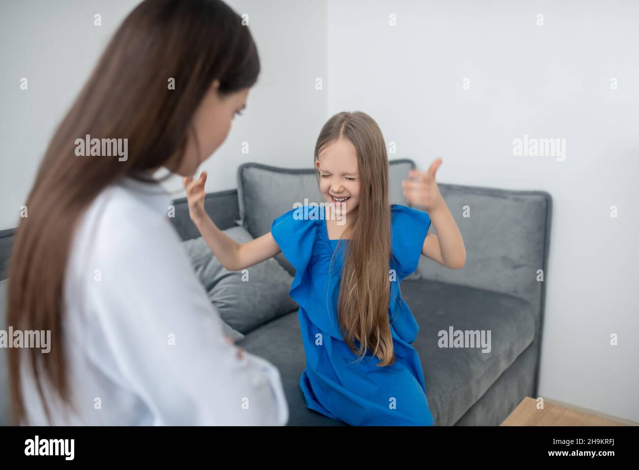 Mother looking at her pleased daughter gesticulating with closed eyes Stock Photo