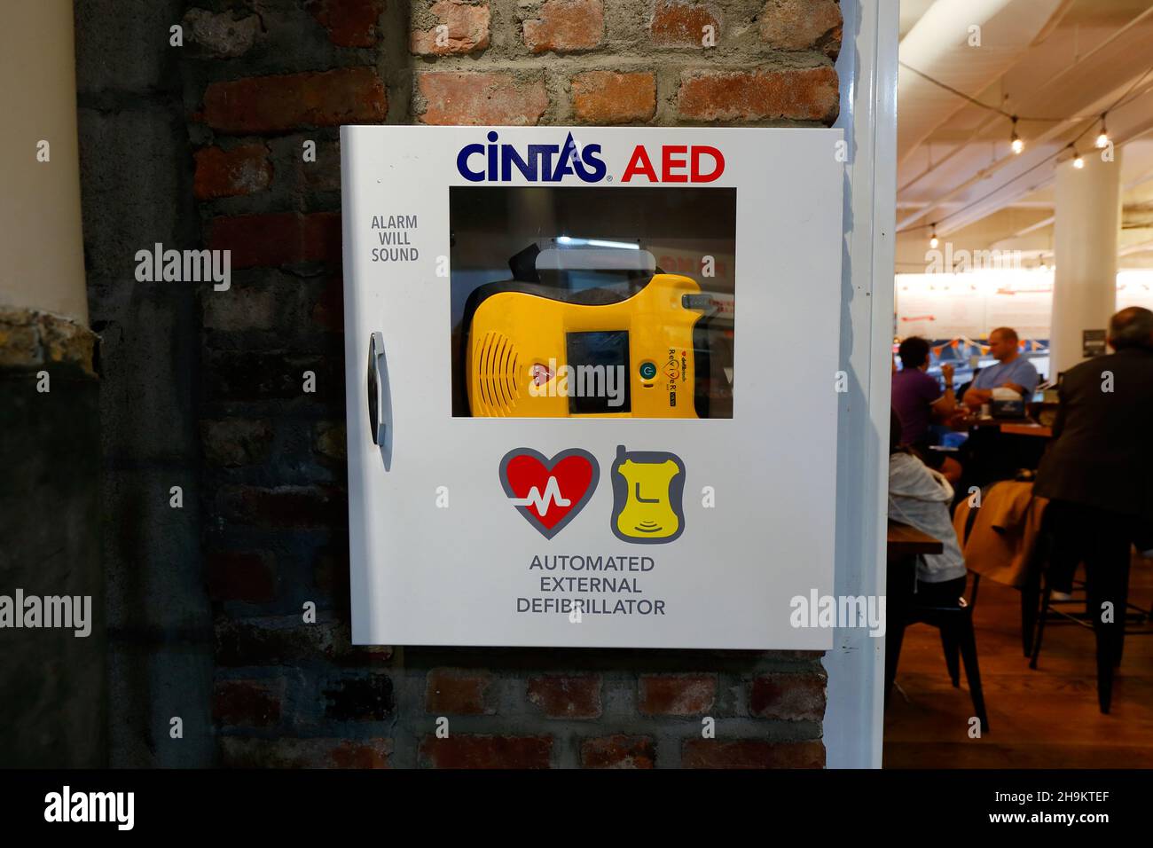 A Cintas Reviver view Automated External Defibrillator (AED) emergency medical device stored inside a wall cabinet in a public space. Stock Photo
