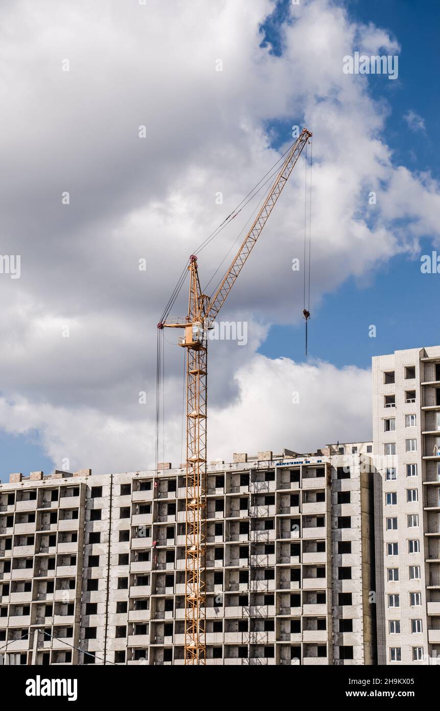 Building crane and building under construction against blue sky. Stock Photo