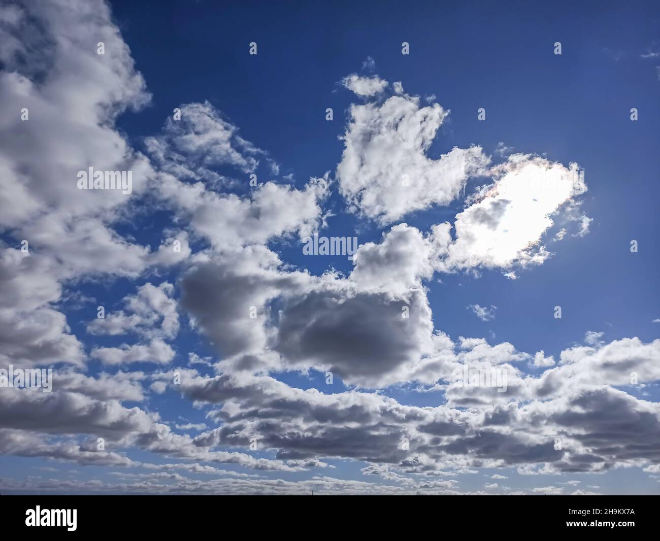 View of a cloudy sky with the sun peeking through the clouds for background Stock Photo
