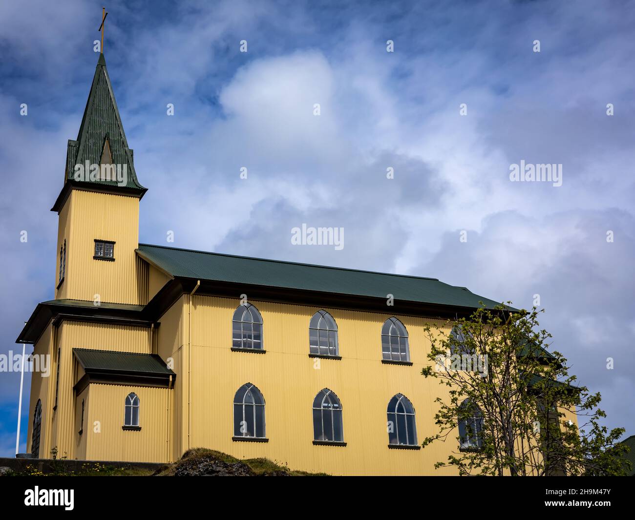 Hafnarfjordur, Iceland - July 17, 2021: A Frikirkjan church in the town center. Traditional icelandic architecture, yellow walls, green rooftop. Stock Photo