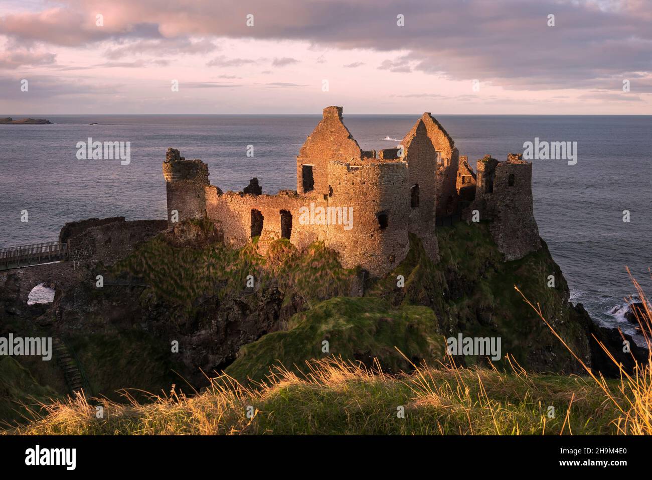 The iconic ruins of Dunluce Castle perched on a rocky outcrop on the North Antrim Coast in Northern Ireland. Stock Photo