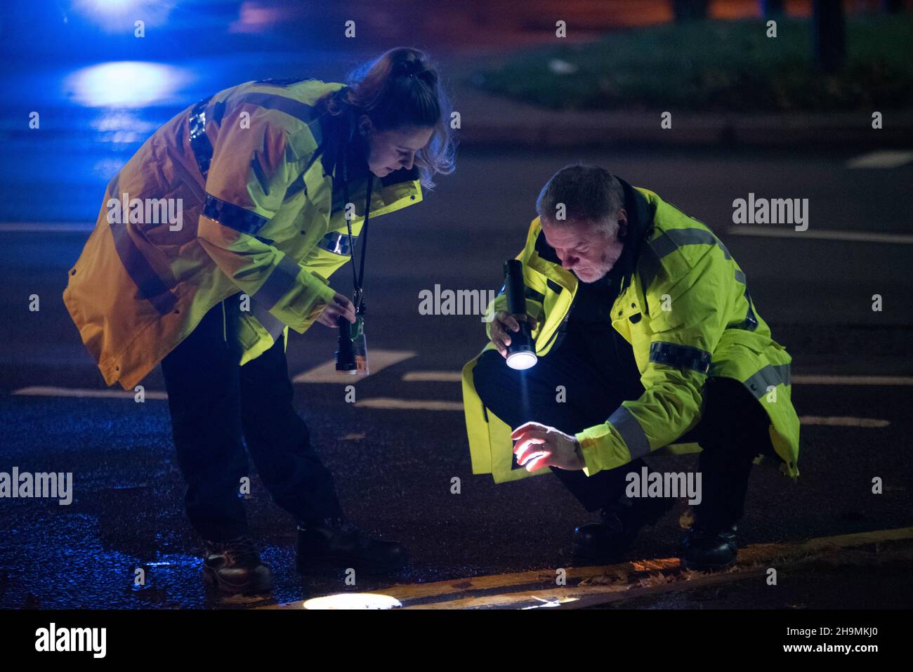 Forensic collision investigators of West Midlands Police, Erdington, Birmingham examining evidence at the scene of a hit and run Stock Photo