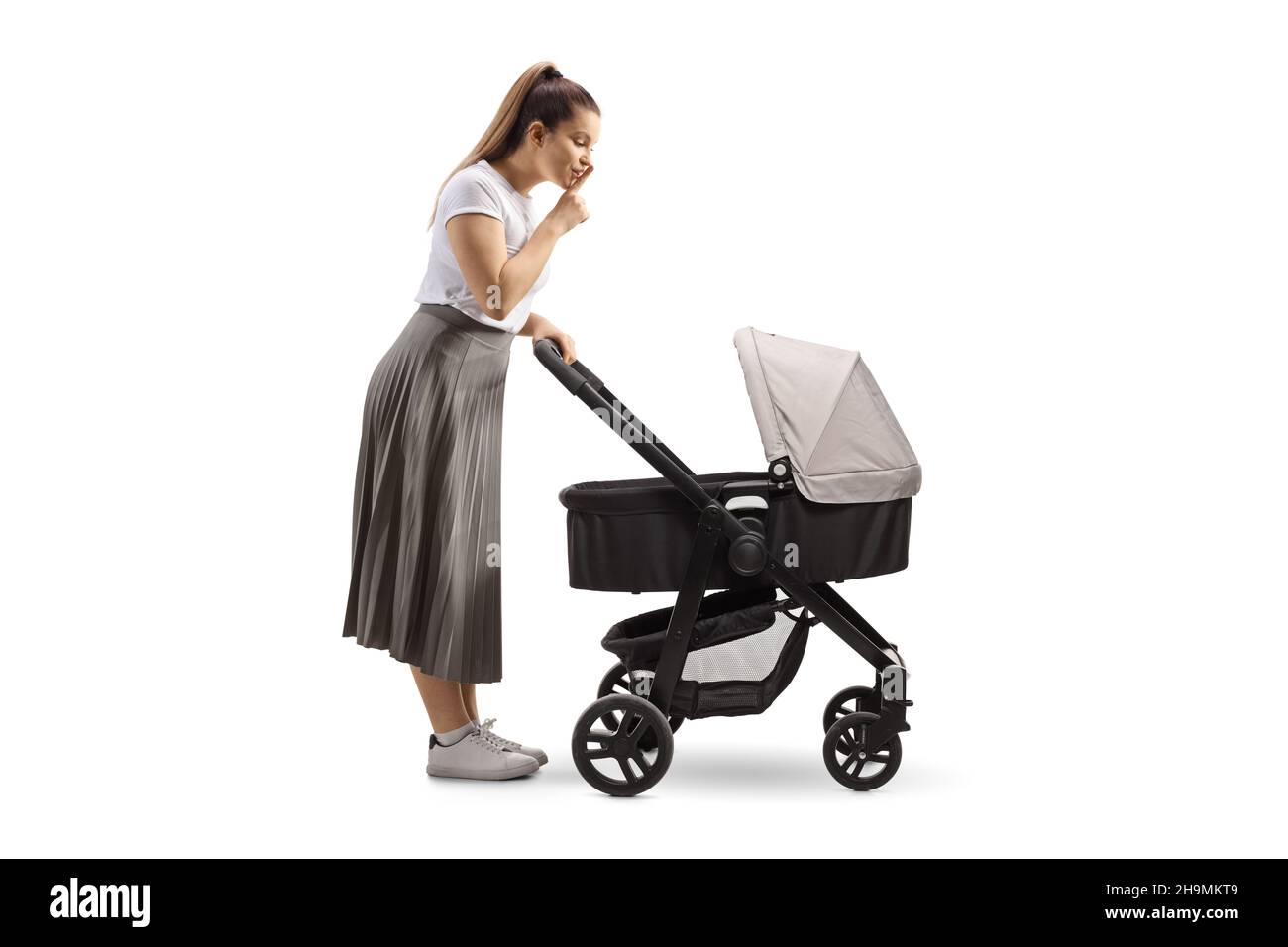 Full length profile shot of a young mother shushing her baby in a pushchair isolated on white background Stock Photo