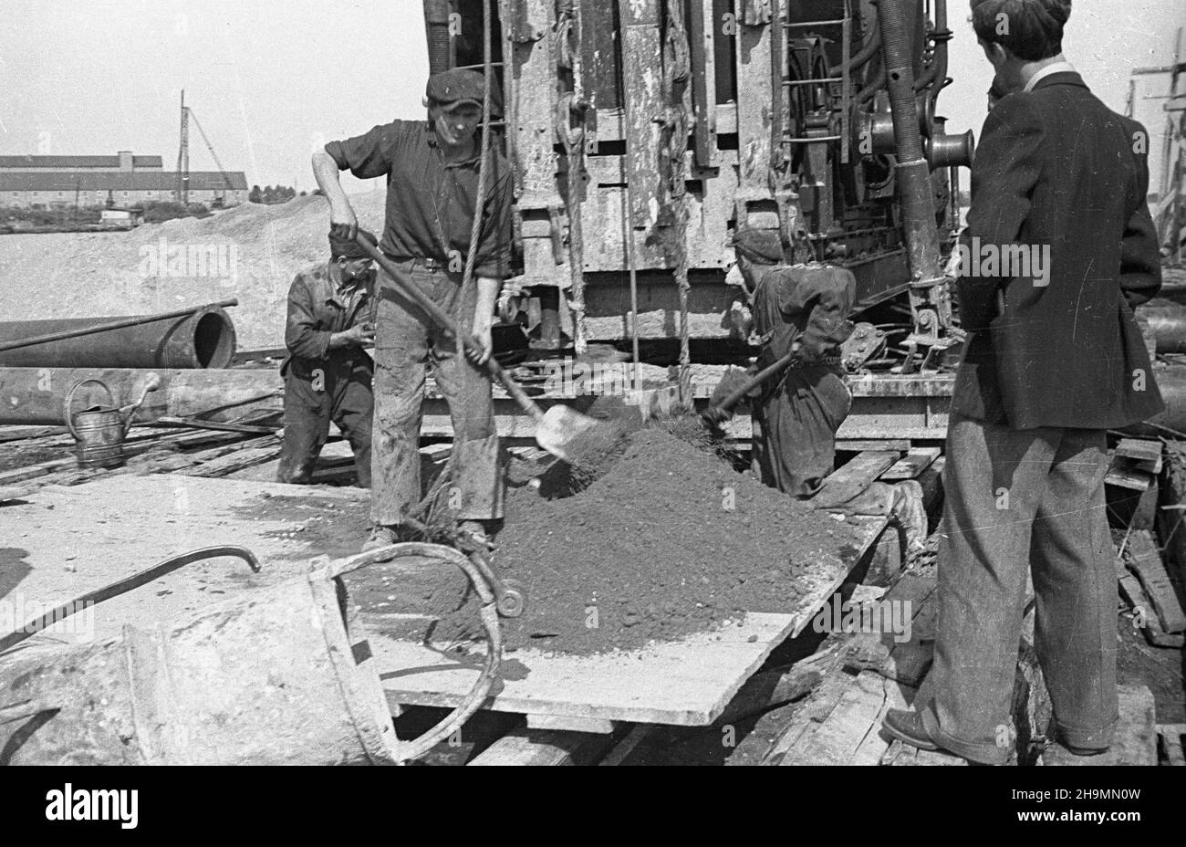 Szczecin, 1948-10. Port Szczecin. Budowa nowego basenu i nabrze¿a prze³adunków masowych. W torfiaste pod³o¿e wbijane s¹ pale, na nich oparte zostan¹ fundamenty pod dŸwigi. Nz.  obs³uga parowego kafara. mw  PAP    Dok³adny dzieñ wydarzenia nieustalony.      Szczecin, Oct. 1948. The  Szczecin port. The construction of a new basin and the cargo re-loading wharf. Pillars are driven into the ground of peat to serve as cranes' founations. Pictured: servicing a steam pile-driver.  mw  PAP Stock Photo