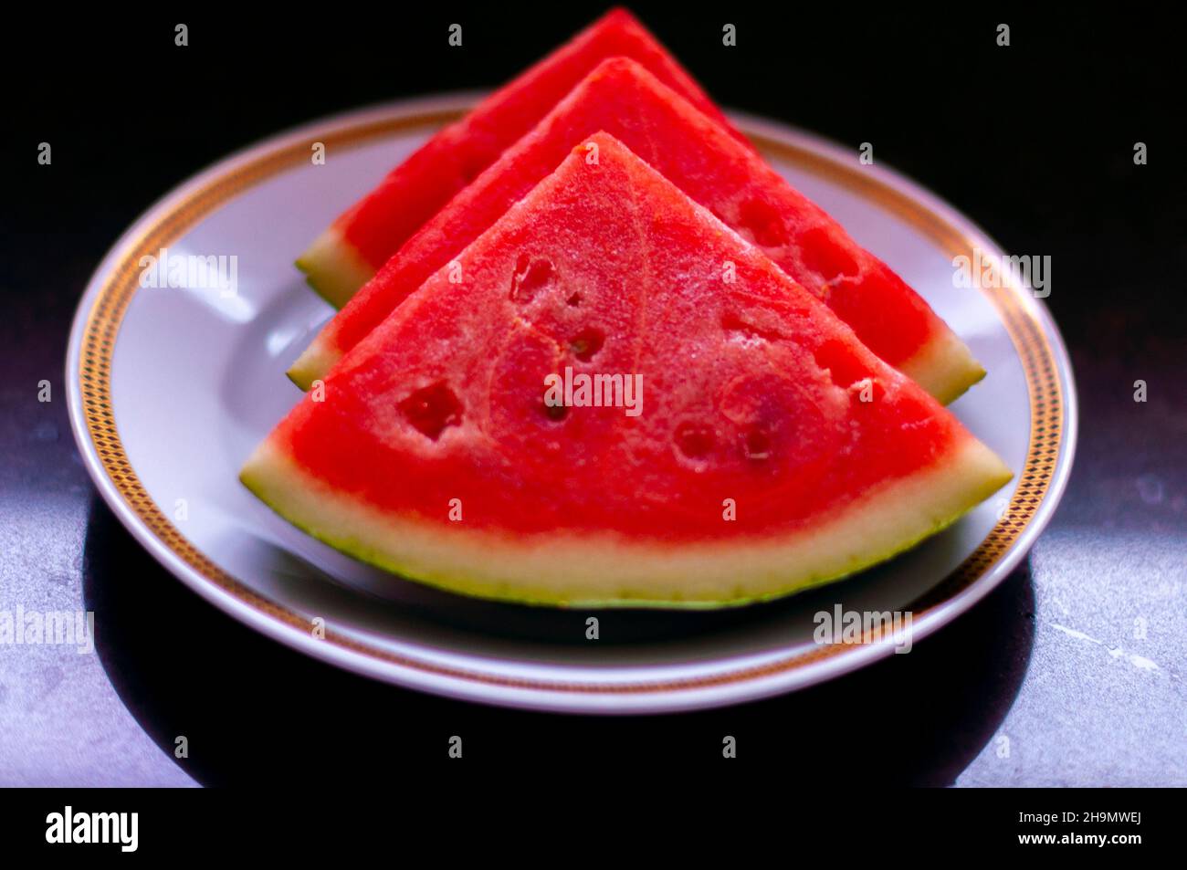 watermelon on a plate. white plate, plate with gold Rim. seedless sliced watermelon. great health benefit. delicious food, seasonal fruit Stock Photo