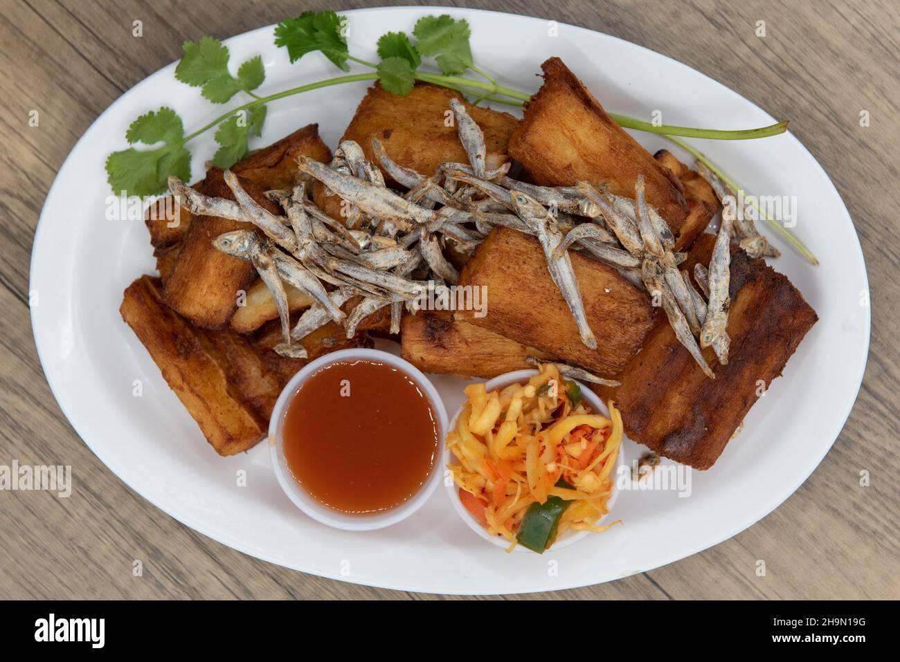 Overhead view of fried Yucca root with garnished with dried fish and dipping sauce for a Latino food delight. Stock Photo