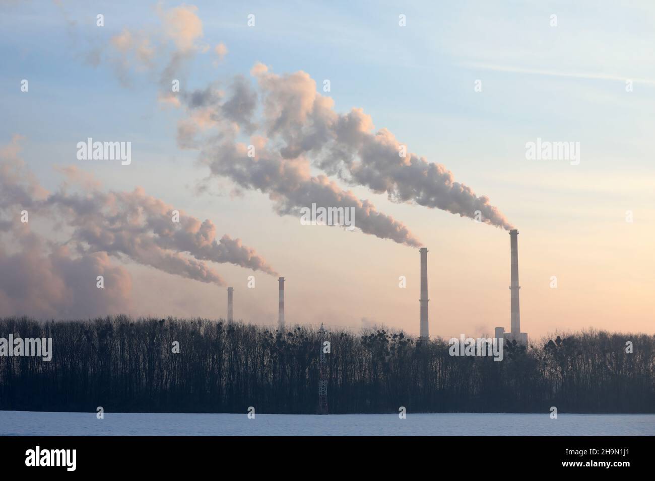 Steam from the factory at sunrise in winter . Stock Photo