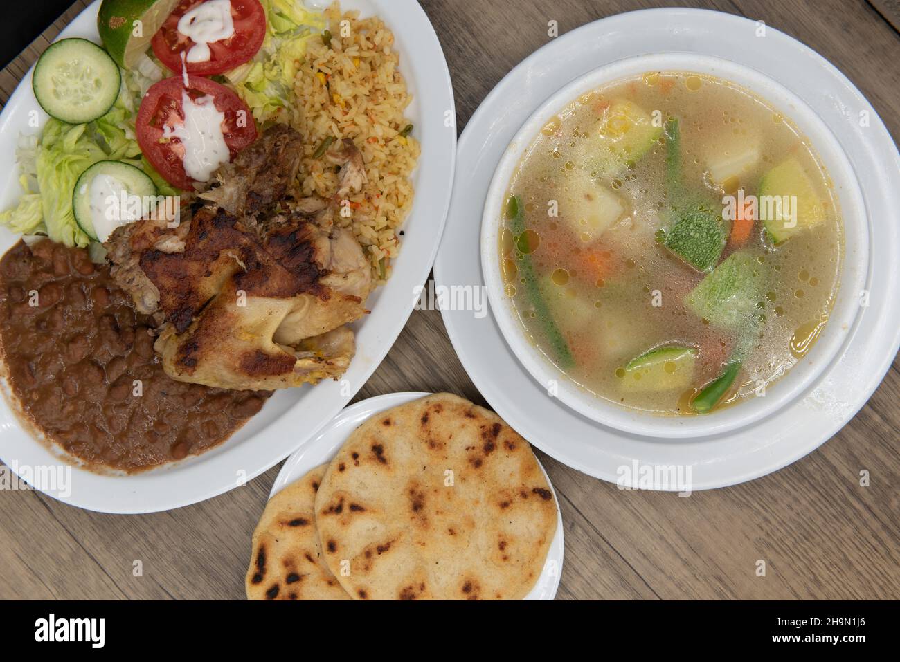 Enormous bowl of Indian soup in a bowl with rice, beans, chicken, and pupusa to make this a very hearty Latino meal. Stock Photo