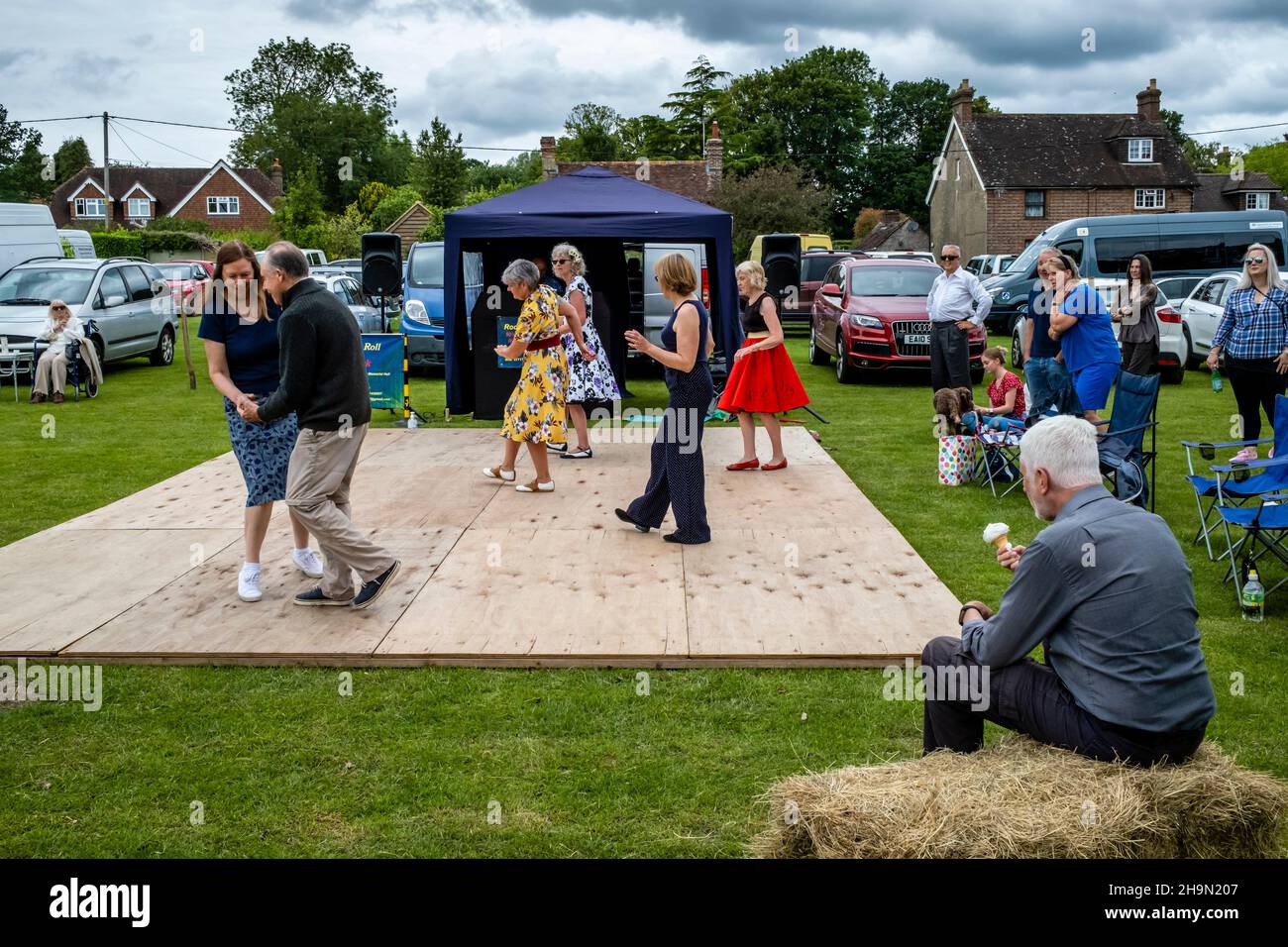 A Man Eats An Ice Cream Whilst Watching Local People Dancing At The Nutley Village Fete, Nutley, East Sussex, UK. Stock Photo