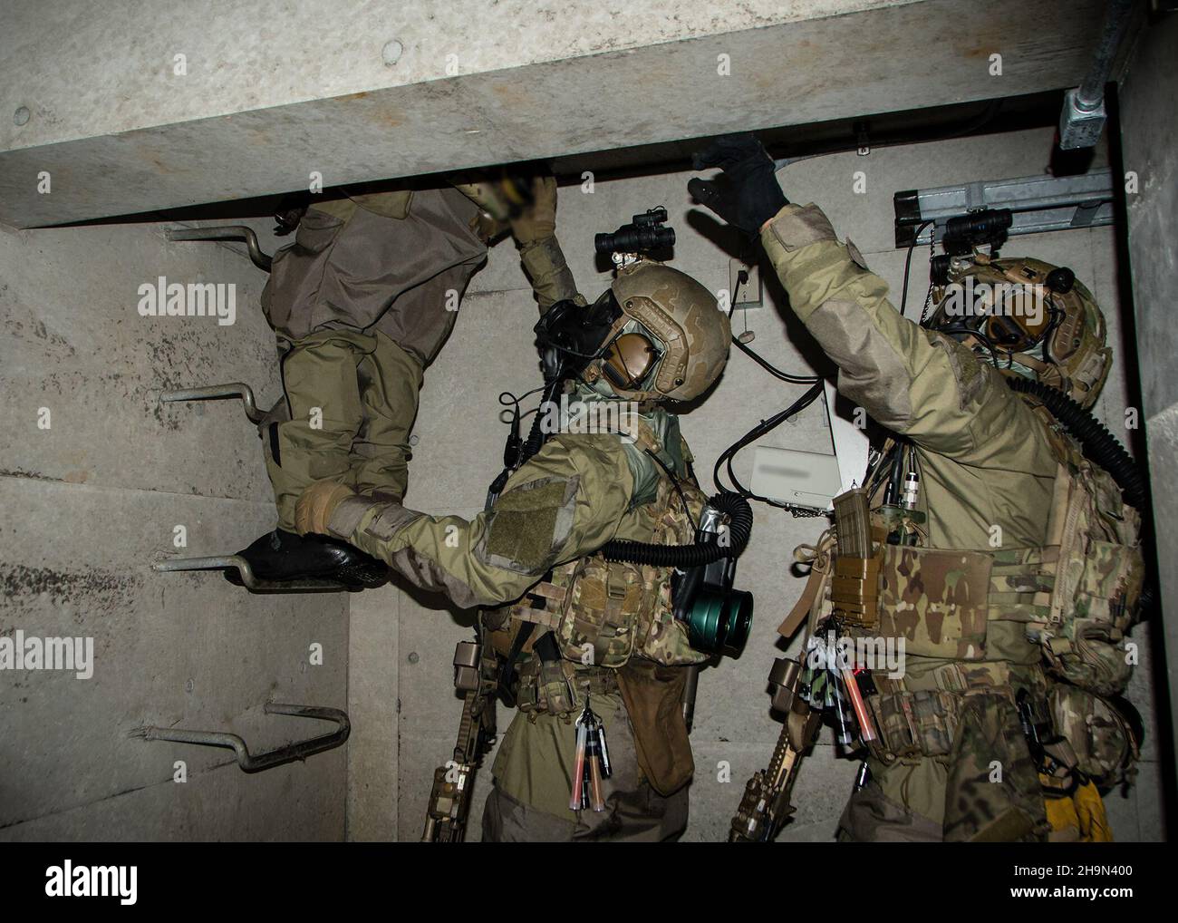 Green Berets with 1st Battalion, 1st Special Forces Group (Airborne),  alongside navy explosive ordnance technicians from Platoon 532, climb a  ladder up to a manhole while conducting direct action training operations on