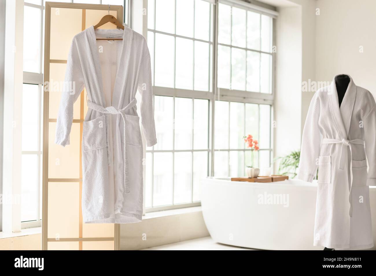 Bathrobes in interior of stylish bathroom with window Stock Photo - Alamy